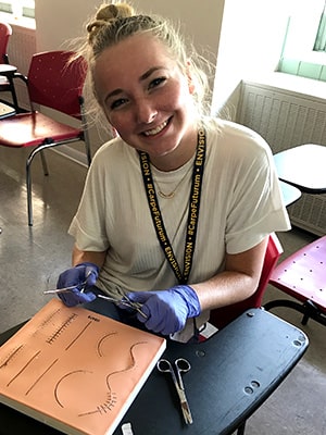 A student practices suturing during an NYLF Medicine clinical skills workshop