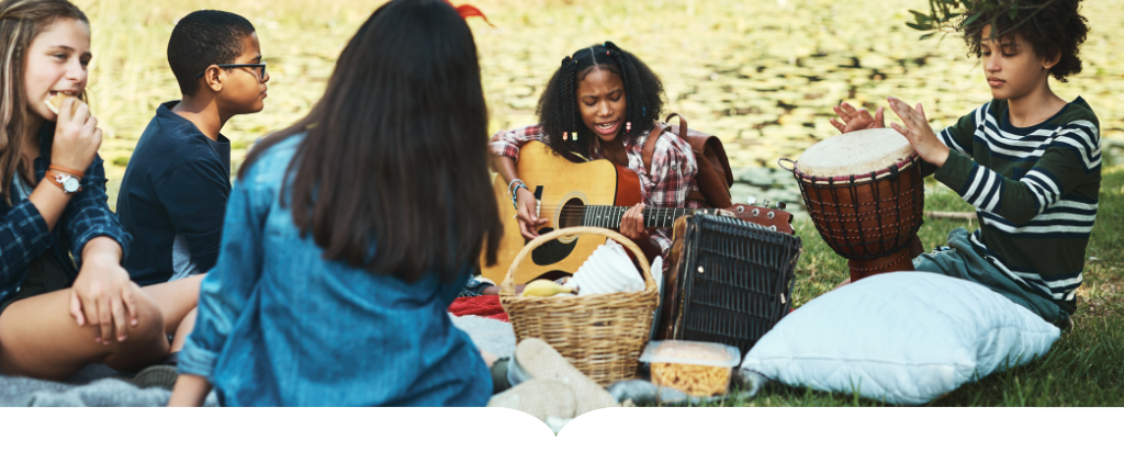 group of students sitting in the grass playing instruments