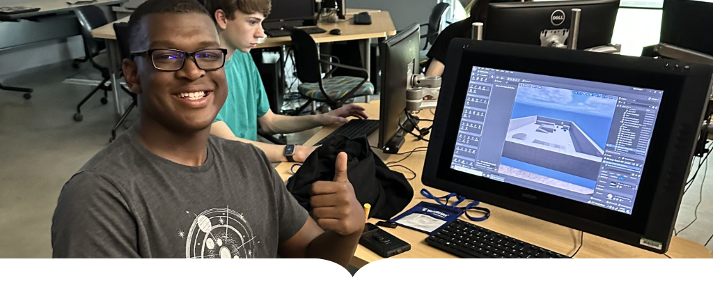 student giving thumbs-up sitting at computer